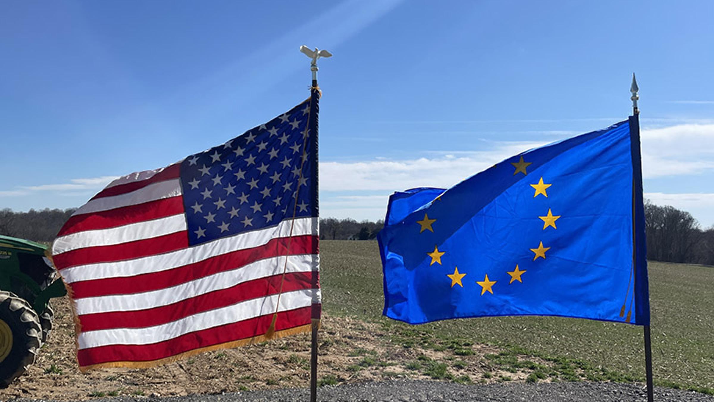 US and EU flags with farm field in background